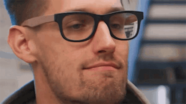 a close up of a man wearing glasses with a reflection of the letter f