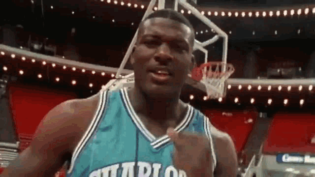 a basketball player in a charlotte hornets jersey is standing in front of a basketball hoop .