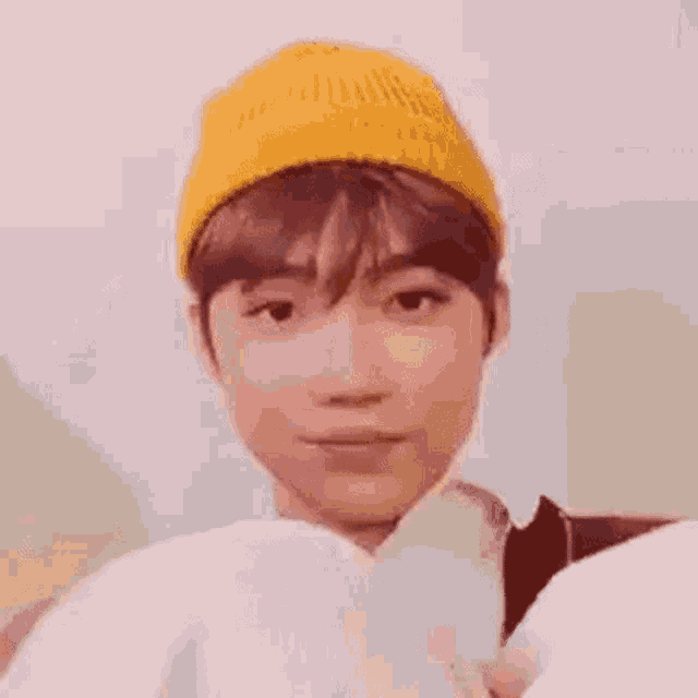 a young man wearing a yellow beanie is sitting on a couch .
