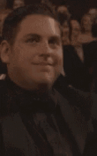 a man in a tuxedo and bow tie is sitting in a theatre .