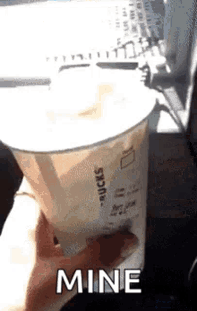 a person is holding a starbucks cup with the word mine written on it