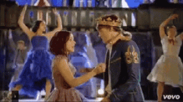 a man in a crown is dancing with a woman in a pink dress .