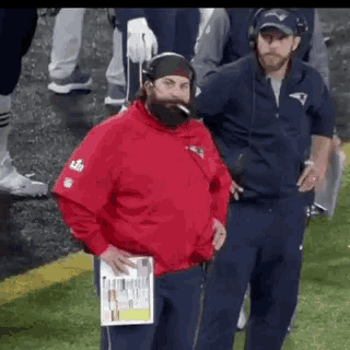 a man with a beard is smoking a cigarette while standing on a field .