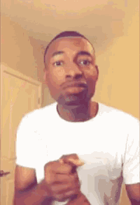 a man in a white shirt is making a funny face with his hands