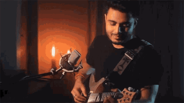 a man in a black shirt is playing a guitar