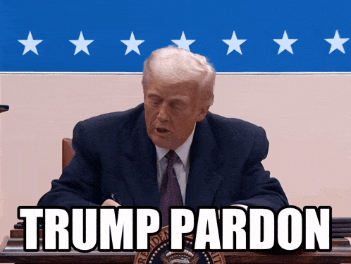 a man in a suit and tie is sitting in front of a sign that says trump pardon on it