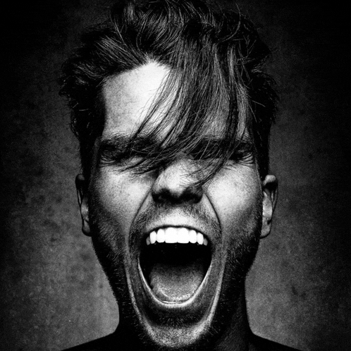 a black and white photo of a man screaming with his mouth wide open