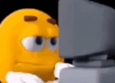a cartoon smiley face is sitting in front of a computer screen .