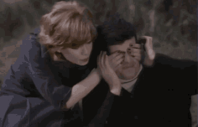 a woman is covering her mouth with her hand while another woman holds her head