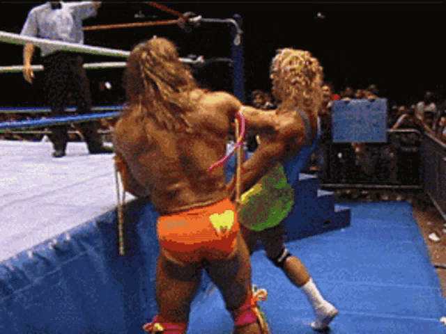 two wrestlers are fighting in a ring with a sign behind them that says ' i love you '