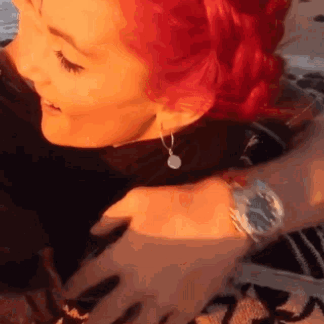 a woman with red hair and a watch on her wrist
