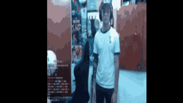 a man wearing headphones and a white shirt is standing in front of a computer .