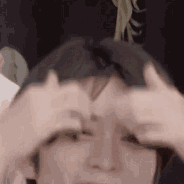 a person is covering their eyes with their hands .