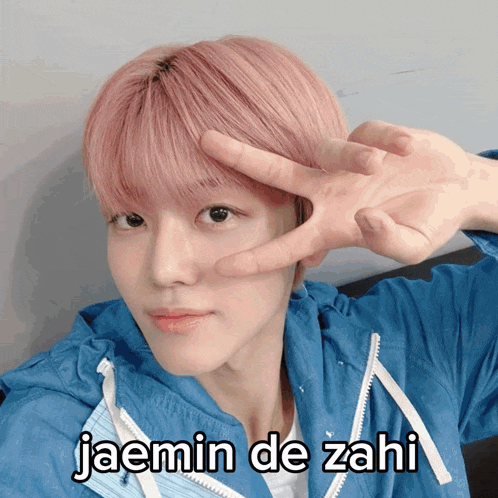 a young man with pink hair is making a peace sign with his hands and the caption jaemin de zahi