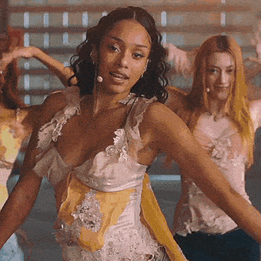 a woman in a white and yellow dress is dancing in front of a group of dancers .