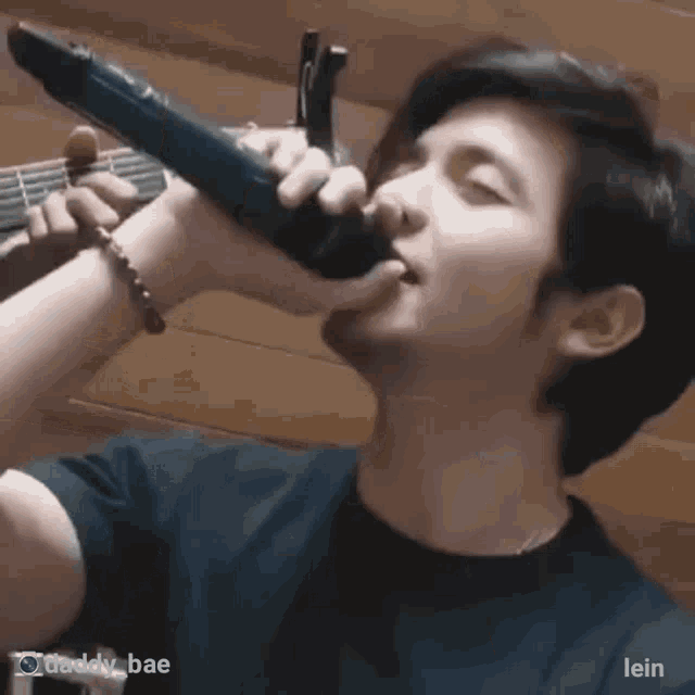 a man is singing into a microphone while holding a guitar in his hand .
