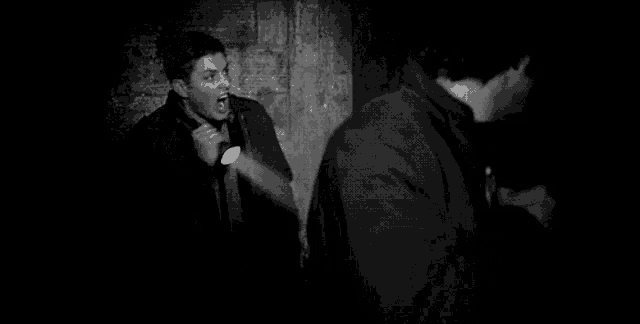 a man is holding a flashlight in a dark room and shouting .