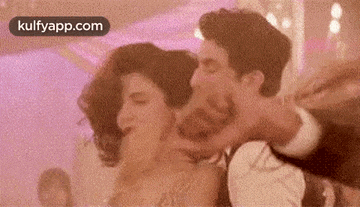 a man is holding a woman in his arms while they are dancing in a room .