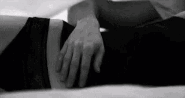 a man is touching a woman 's stomach while laying on a bed .