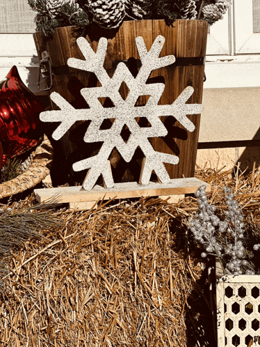 a wooden snowflake sitting on a pile of hay