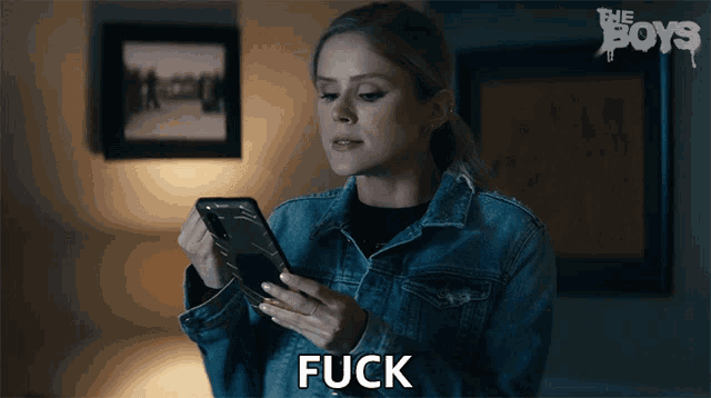 a woman in a denim jacket is holding a cell phone and the word fuck is above her