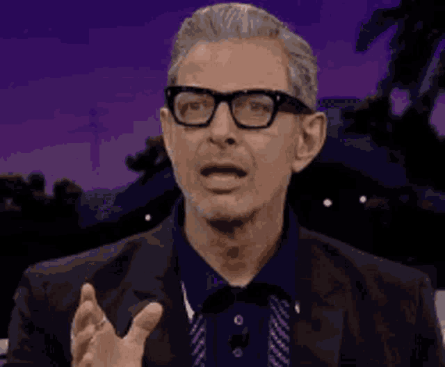 a man wearing glasses and a suit is making a funny face .