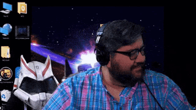 a man wearing headphones stands in front of a computer screen with a robot in the background