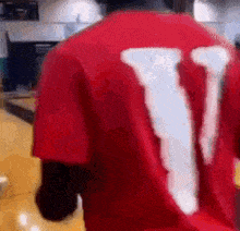 a person wearing a red shirt with the letter v on the back is walking down a hallway .