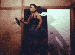 a man in a black tank top is holding a dumbbell in a doorway