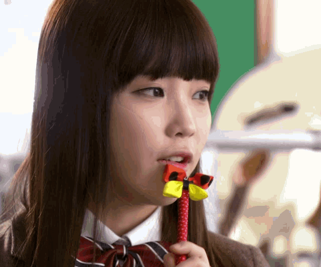 a girl with a bow in her mouth is holding a pen