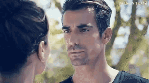 a man and a woman are looking at each other . the man is wearing a black shirt .