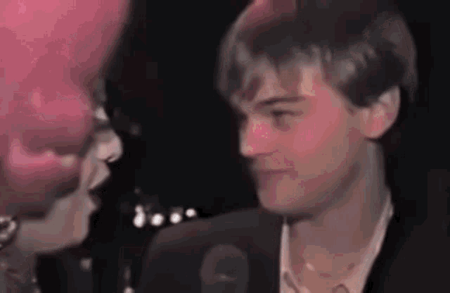 a man and a woman are talking to each other in front of a microphone in a dark room .