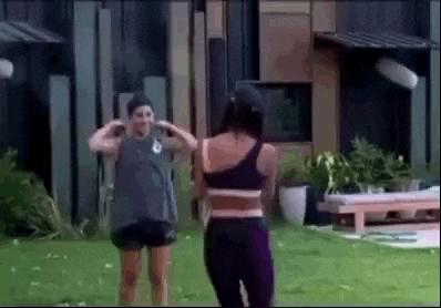 two women are standing in front of a building in a yard .