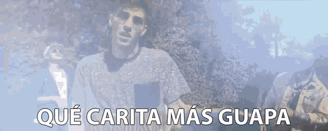 a man is covering his face with his hands and the words que carita mas guapa are written below him