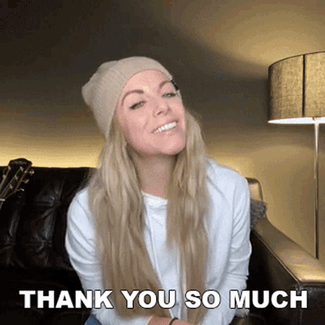 a woman wearing a beanie is sitting on a couch and smiling with the words thank you so much above her