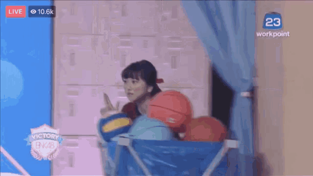 a woman is holding a volleyball in front of a screen that says live