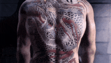 a man with a dragon tattoo on his back has the letter t on his chest