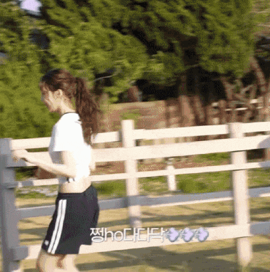 a woman in a white crop top and black shorts is running behind a fence
