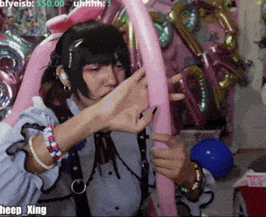 a person is holding a pink balloon in front of balloons and says heep xing