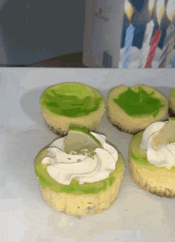 three cupcakes with green frosting and whipped cream on them
