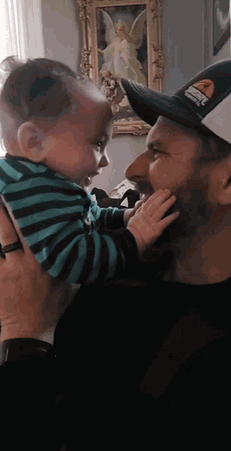 a man holding a baby wearing a hat that says ' jacksonville ' on the front