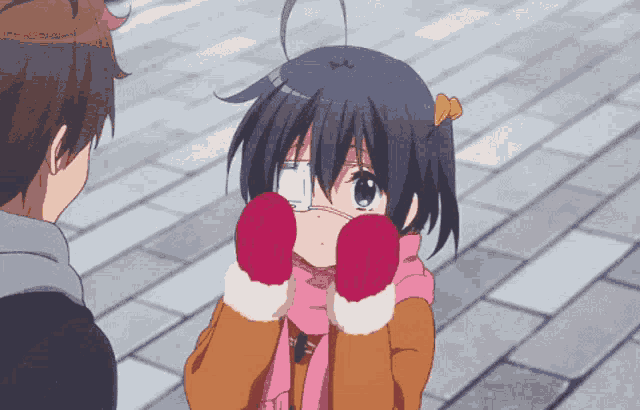 a girl wearing red gloves and a scarf looks at a boy