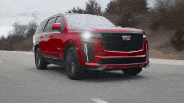 a red cadillac is driving down a highway