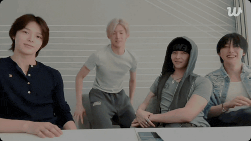 a group of young men are sitting around a table and one of them is wearing a beanie that says owe on it