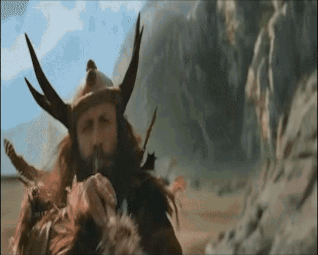 a man with a beard is wearing a helmet with horns and feathers