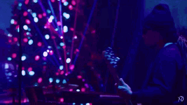 a man is playing a dj set in a dark room with a christmas tree in the background ..
