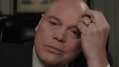 a bald man with a wedding ring on his finger looks down