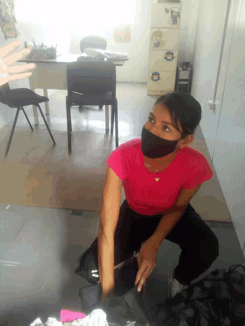 a woman wearing a face mask is kneeling down in front of a desk
