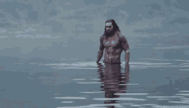 a shirtless man with a beard is standing in the water .