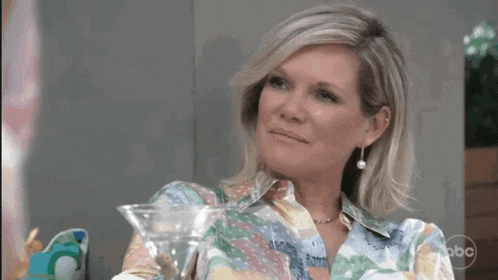 a woman is holding a martini glass in her hand and saying life is good .